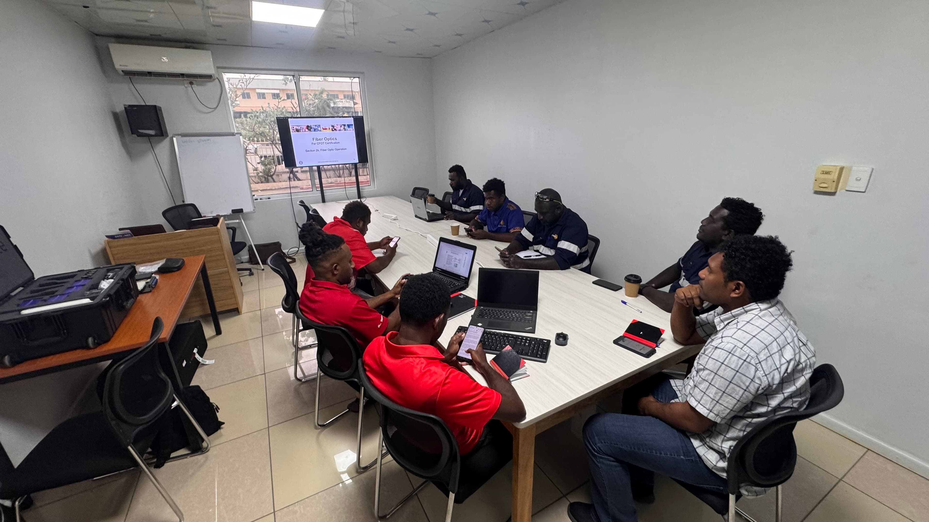 Technical training session in Honiara with participants gathered around a classroom table